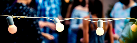String lights with people at an outdoor event in the background
