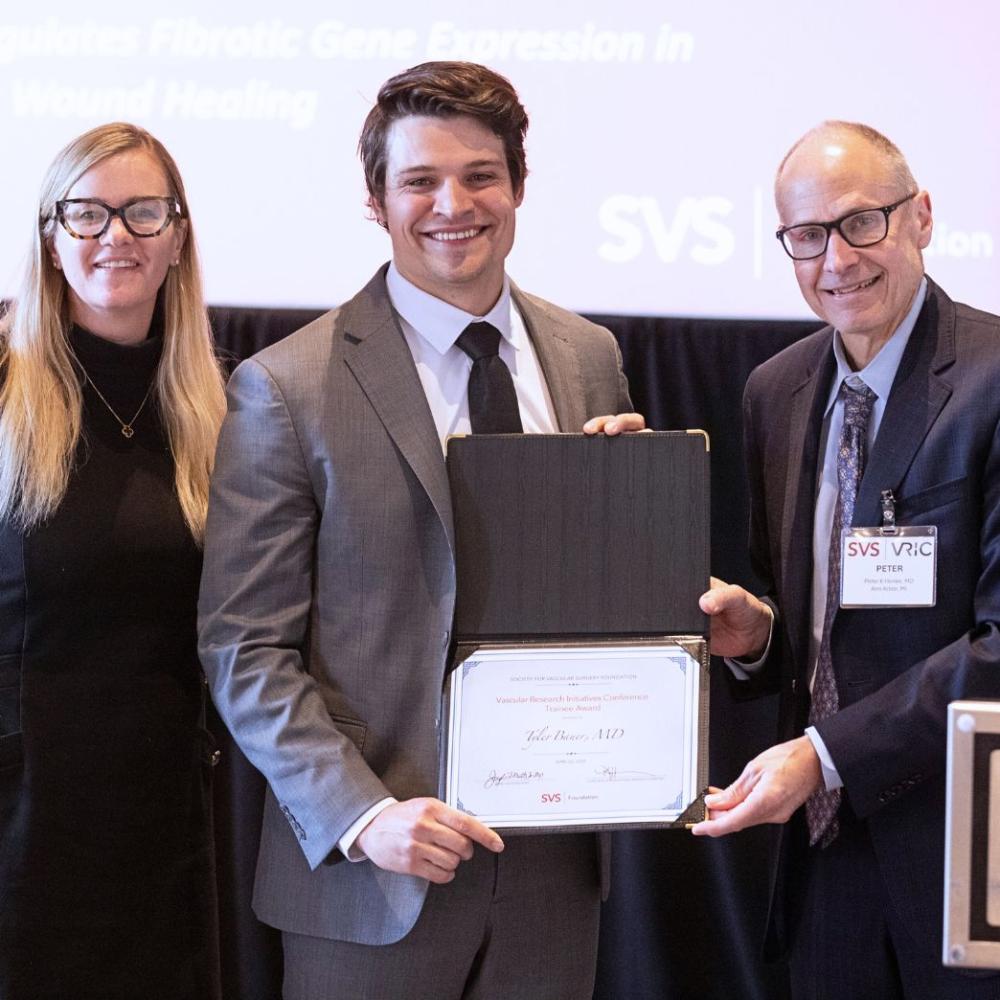 person standing with award and two other people standing on either side of them